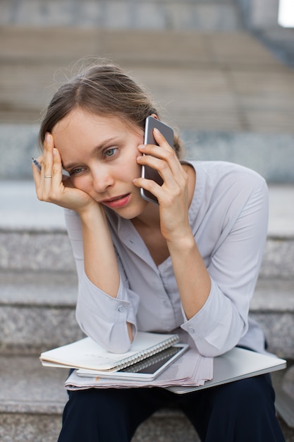 Femme d&#39;affaires fatigué appelant le client dans les escaliers