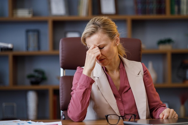 Femme d'affaires fatiguée après avoir épuisé la paperasse en enlevant les lunettes se sentant mal à la tête mal de tête mauvaise vision fatigue chronique et concept de fatigue oculaire concept d'épuisement professionnel et de surmenage