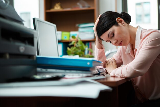 Femme d'affaires fatiguée dormant sur le bureau