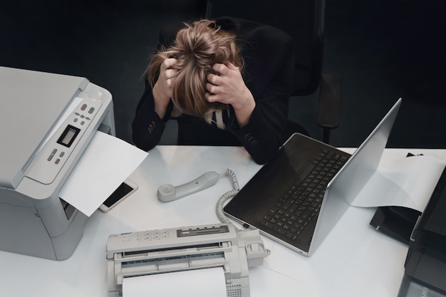 Une femme d'affaires fatiguée et stressée se sent épuisée assise au bureau avec un ordinateur portable