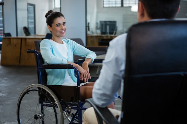 Femme d'affaires en fauteuil roulant, parler avec un collègue au bureau