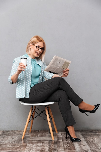 Femme d'affaires gai boire du café en lisant le journal.