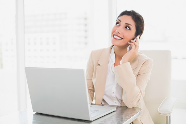 Femme d&#39;affaires gai travaillant avec un ordinateur portable sur le téléphone