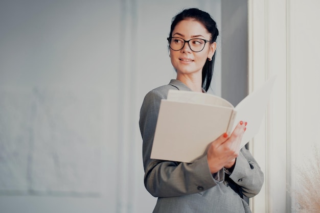 Une femme d'affaires une gestionnaire brune avec des lunettes lit un livre