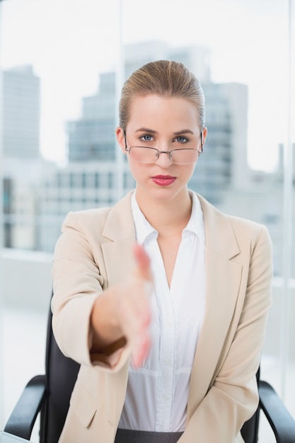 Femme d&#39;affaires grave avec des lunettes présentant sa main