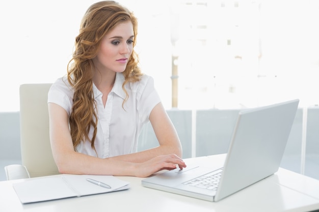 Femme d&#39;affaires grave utilisant un ordinateur portable au bureau