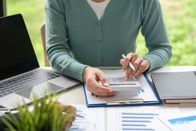 Femme d'affaires en gros plan tenant un stylo à l'aide d'une calculatrice pour calculer la comptabilité, les statistiques et les concepts de travail au bureau.