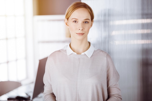 Femme d'affaires habillée décontractée adulte amicale debout tout droit. Concept d'une photo d'entreprise ou d'un portrait au bureau.