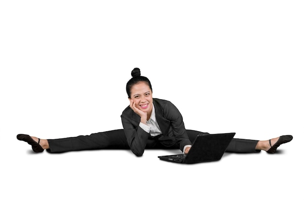 Une femme d'affaires heureuse assise en splits dans un studio.