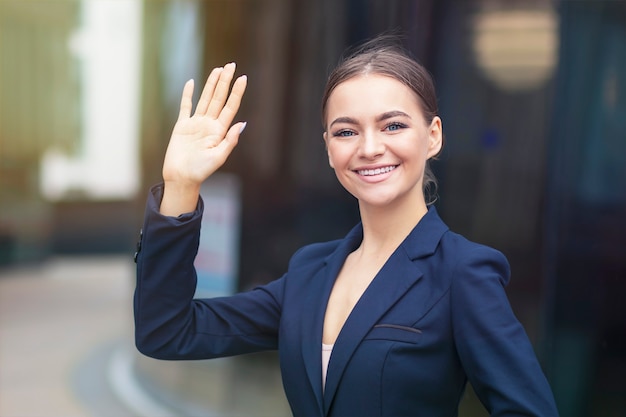 Femme d'affaires heureuse habillée formelle agite sa main à l'extérieur