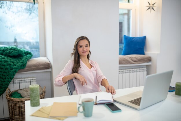 Femme d'affaires heureuse positive assis dans son bureau tout en travaillant