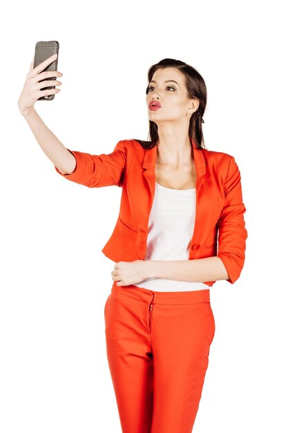 Femme d'affaires heureuse prenant selfie photo smartphone modèle d'affaires des femmes en costume rouge isolé sur fond blanc