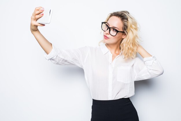 Femme d'affaires heureuse prenant smartphone photo selfie isolé sur blanc. Modèle d'affaires des femmes en costume.