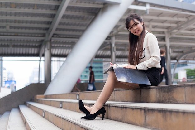 Femme d&#39;affaires heureux assis sur le trottoir.