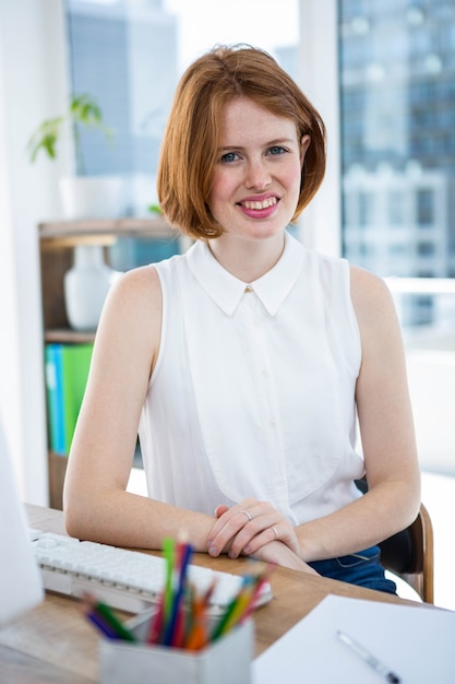 femme d'affaires de hipster souriant assis dans son bureau avec ses mains sur le bureau