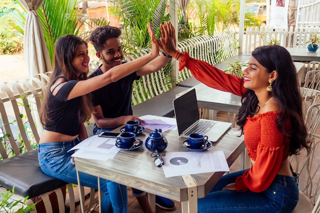 Femme d'affaires et homme d'affaires indiens prospères au travail surfant en freelance en ligne indépendante dans un café tropical d'été.trois amis communiquant avec du thé se rencontrant