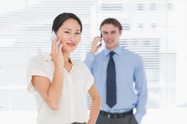 Femme d&#39;affaires et homme à l&#39;aide de téléphones portables au bureau