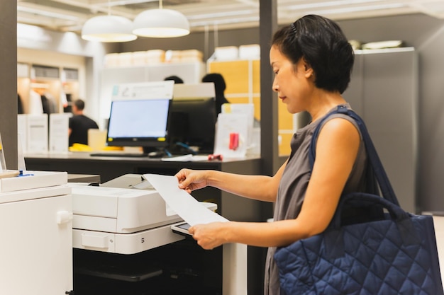 Photo une femme d'affaires imprime sur l'imprimante du bureau.