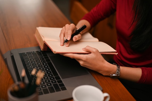 Une femme d'affaires inscrit quelque chose sur son ordinateur portable tout en travaillant à son bureau