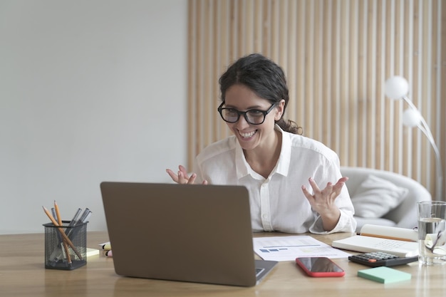 Une femme d'affaires italienne ravie de lire de bonnes nouvelles sur un ordinateur portable sur son lieu de travail