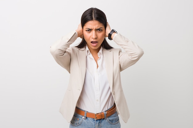 Femme d&#39;affaires jeune arabe isolé blanc couvrant les oreilles avec les mains en essayant de ne pas entendre un son trop fort.