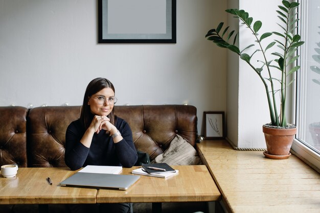 Femme d'affaires jeune assis à table et prendre des notes dans le cahier.