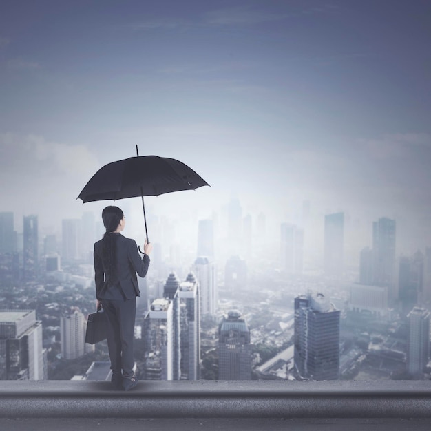 Femme d'affaires jeune avec parapluie sur le toit