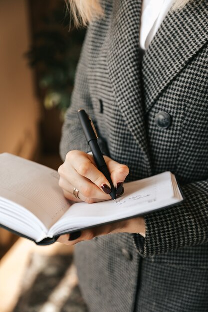 Femme d'affaires jeune prend des notes dans un cahier au bureau.