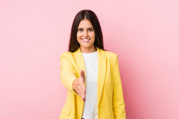 Femme d'affaires jeune qui s'étend de la main à la caméra en geste de voeux.