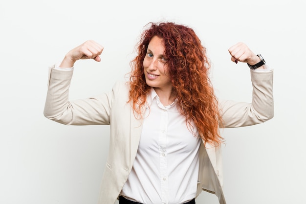 Femme d'affaires jeune rousse naturelle isolée sur fond blanc montrant le geste de la force