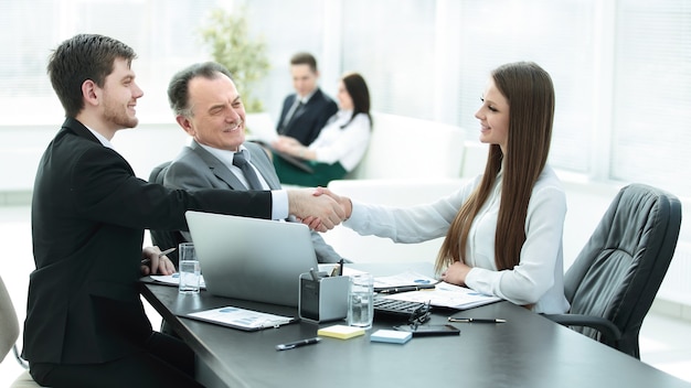 Femme d'affaires jeune serrant la main d'un partenaire commercial adulte.