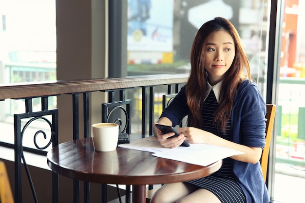 Femme d&#39;affaires jeune avec smartphone et café