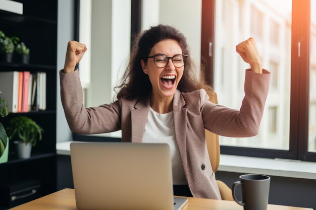 Photo une femme d'affaires joyeuse, un entrepreneur indépendant souriant et se réjouissant de la victoire alors qu'il est assis à son bureau.