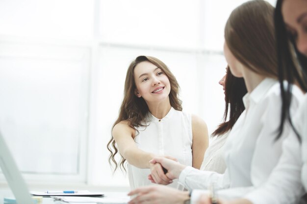 Femme d'affaires joyeuse et poignée de main client assis à la table