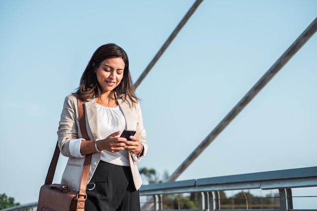 Femme d'affaires lisant son smartphone dans la rue Espace de copie Femme d'affaires lisant son smartphone