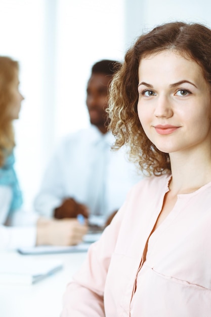 Femme d'affaires lors d'une réunion au bureau, colorée en blanc. Groupe multiethnique de gens d'affaires.