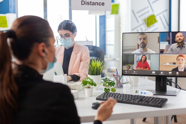 Femme d'affaires lors de la suppression de la vidéoconférence sur ordinateur portant un masque facial comme mesure de sécurité pendant la pandémie mondiale avec la grippe covid19 dans un nouveau lieu de travail normal. Appel vidéo virtuel sur Internet en ligne