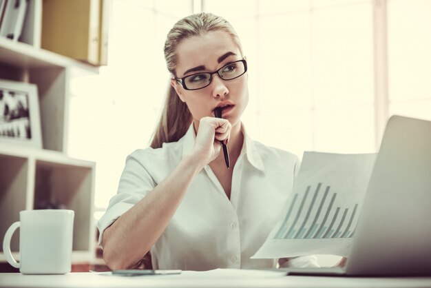 Femme d'affaires à lunettes étudie des documents.