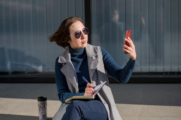 Femme d'affaires à lunettes de soleil avec ordinateur portable assis dans la ville d'automne. Photo de haute qualité