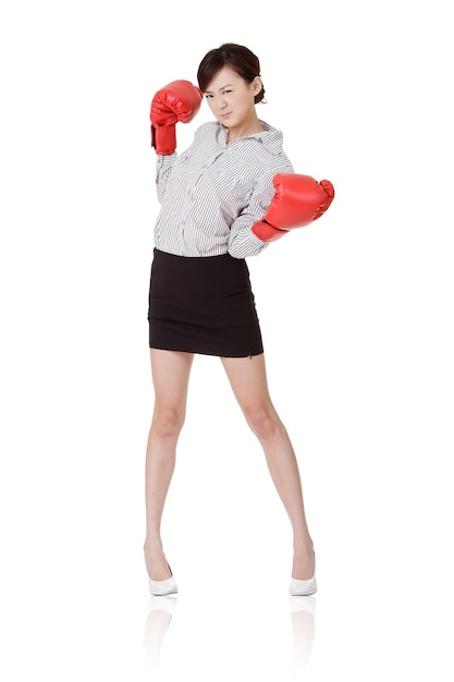 Femme d'affaires lutte avec des gants de boxe, isolés sur un mur blanc.