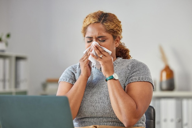 Femme d'affaires malade ou malade souffrant d'une grippe froide ou d'une infection des sinus et éternuant ou se mouchant avec un mouchoir Jeune femme travaillant à distance sur son ordinateur portable depuis le bureau à domicile