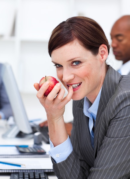 Femme d&#39;affaires mangeant un fruit au travail