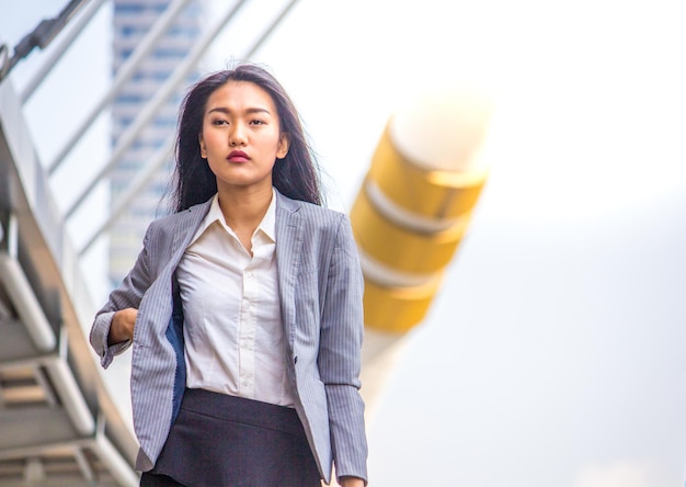 Une femme d'affaires marche contre un bâtiment.