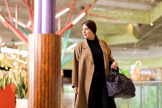 Photo une femme d'affaires marche en toute confiance habillée avec élégance avec un manteau et un sac à main en souriant et en regardant sur le côté