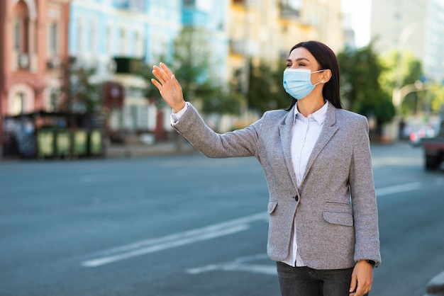 Femme d'affaires avec masque médical en agitant dans la rue