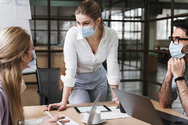 Photo femme d'affaires avec masque médical tenant une réunion professionnelle