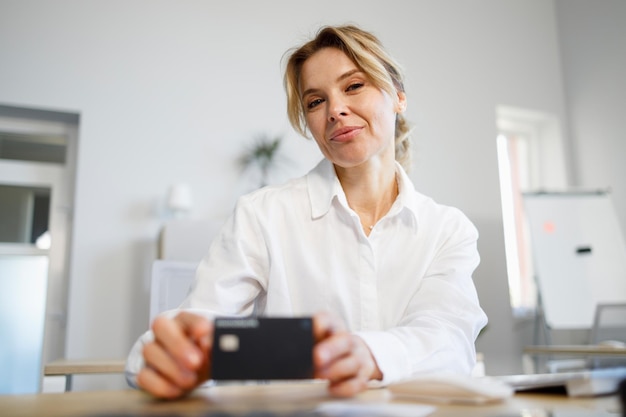 Femme d'affaires mature détenant une carte de crédit