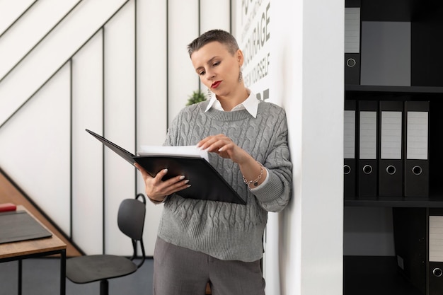 Femme d'affaires mature avec un dossier pour les documents dans ses mains se tient au bureau