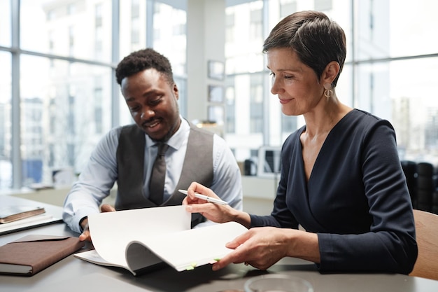 Photo une femme d'affaires mature et élégante signe des documents avec un collègue au bureau.