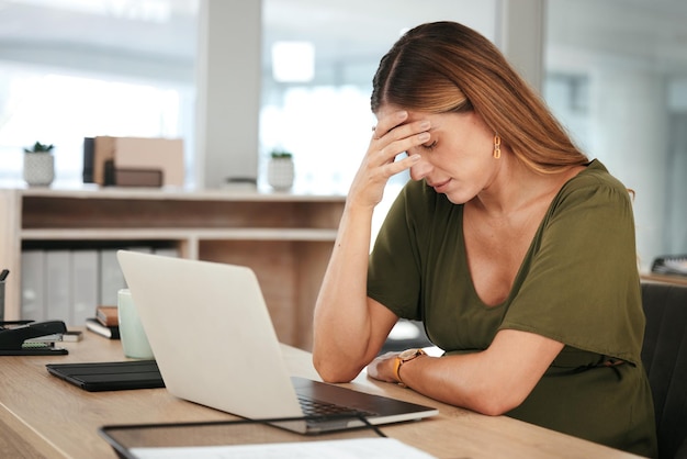 Femme d'affaires et maux de tête au bureau avec épuisement fatigué et se détendre avec les yeux fermés au bureau ou à la table Personne professionnelle et employée avec la main sur le visage pour l'anxiété ou le stress dans l'entreprise